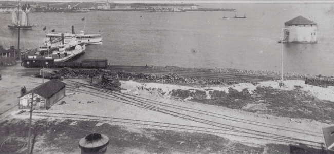 Photograph looking towards Point Frederick from Railway Yard - Two ships docked on left - Ferry "Maud" passing by. 1885.